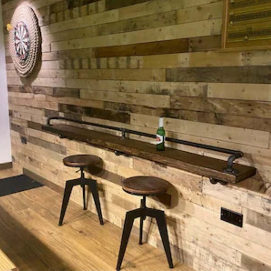 Reclaimed pallet wood ideal for rustic look cladding showcased in a stylish bar setting with stools and a dartboard.